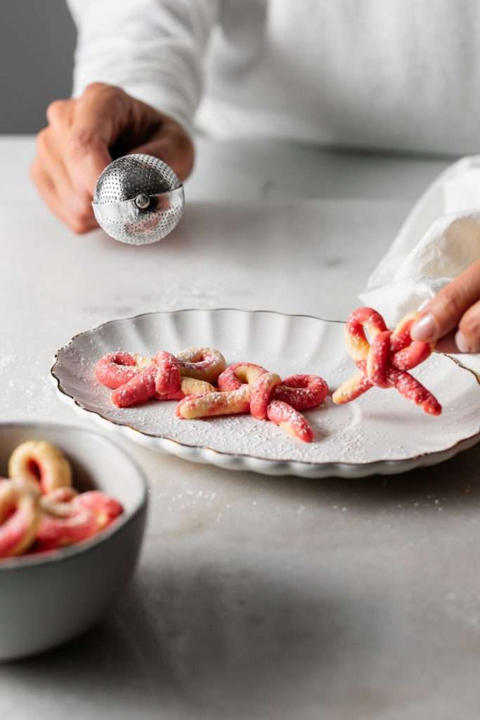Peppermint infused candy cane bow sugar cookies shaped and twisted into bows and arranged on a holiday themed surface.