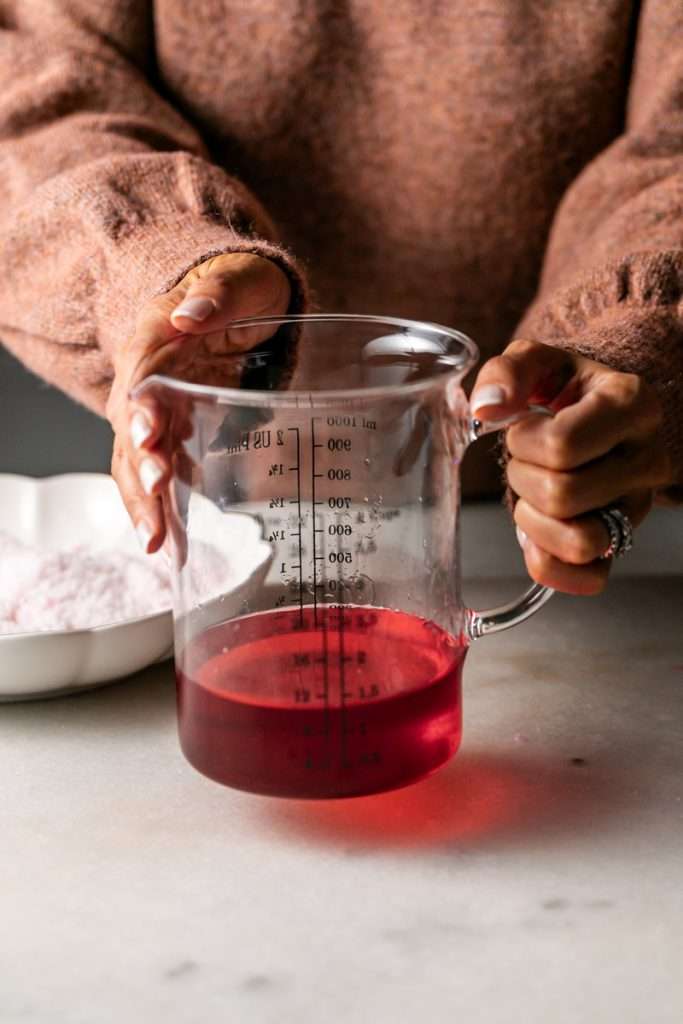Sparkling sugared cranberries coated in sugar in a glass dish, perfect as a festive holiday garnish.