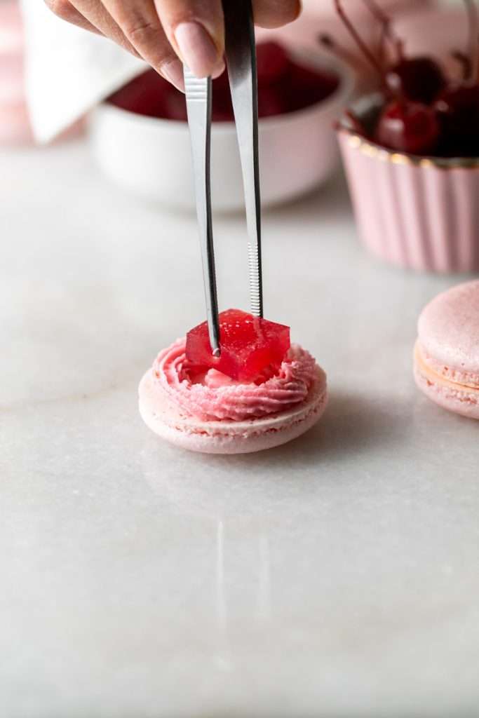 Shirley Temple macarons filled with cherry grenadine gel, and lime buttercream, toped with a glossy cherry.