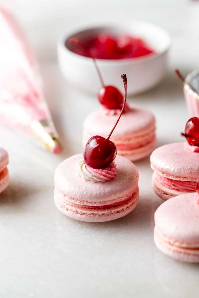 Shirley Temple macarons filled with cherry grenadine gel, and lime buttercream, toped with a glossy cherry.