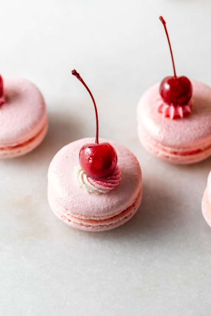 Shirley Temple macarons filled with cherry grenadine gel, and lime buttercream, toped with a glossy cherry.