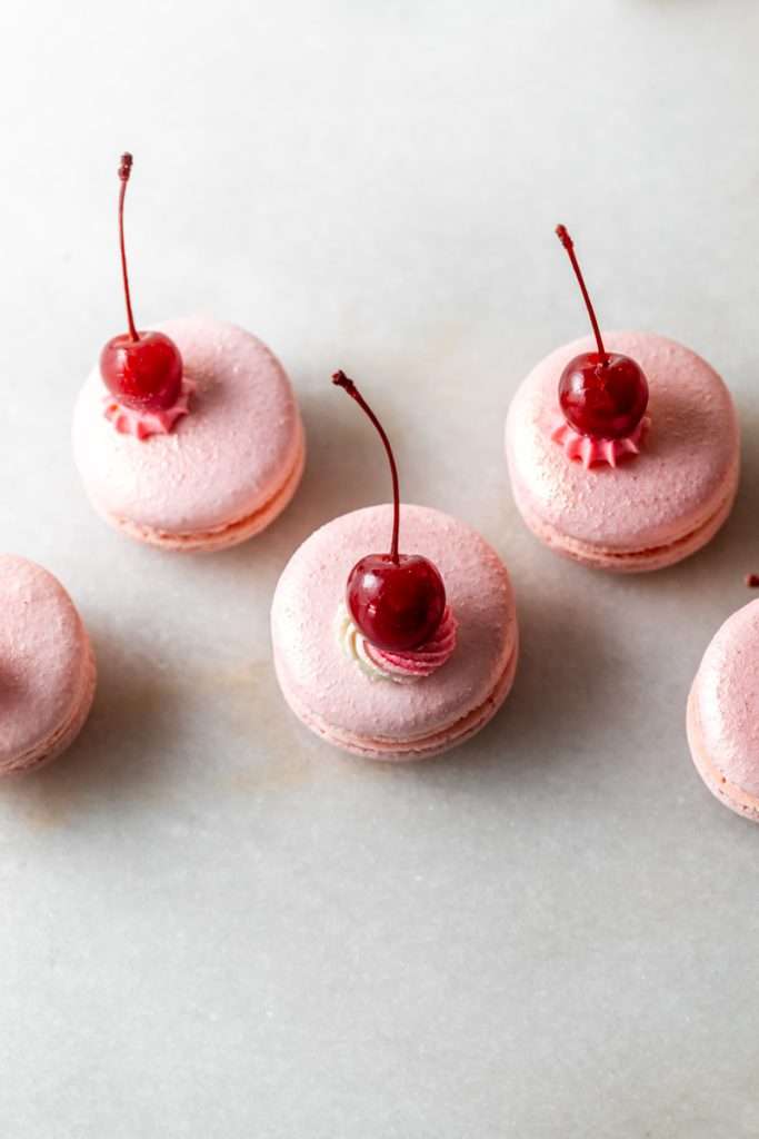 Shirley Temple macarons filled with cherry grenadine gel, and lime buttercream, toped with a glossy cherry.