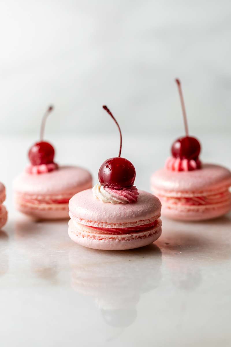 Shirley Temple macarons filled with cherry grenadine gel, and lime buttercream, toped with a glossy cherry.
