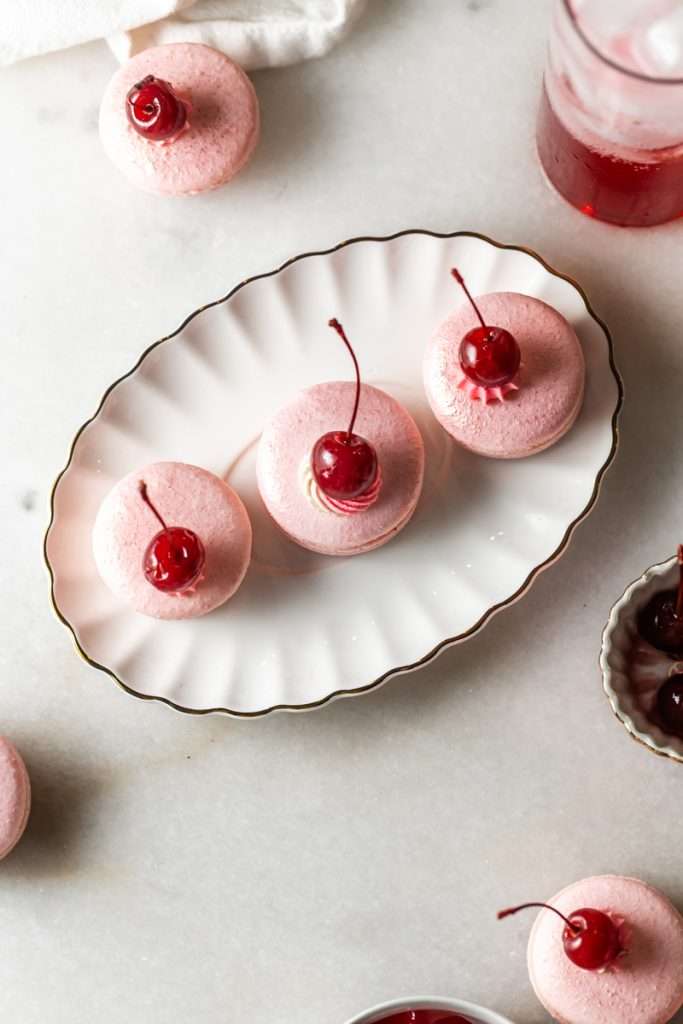 Shirley Temple macarons filled with cherry grenadine gel, and lime buttercream, toped with a glossy cherry.