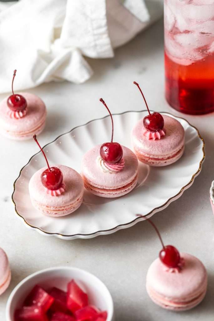 Shirley Temple macarons filled with cherry grenadine gel, and lime buttercream, toped with a glossy cherry.