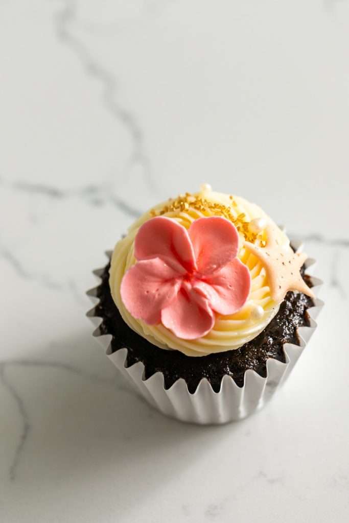 Tropical birthday cupcake decorated with royal icing plumeria