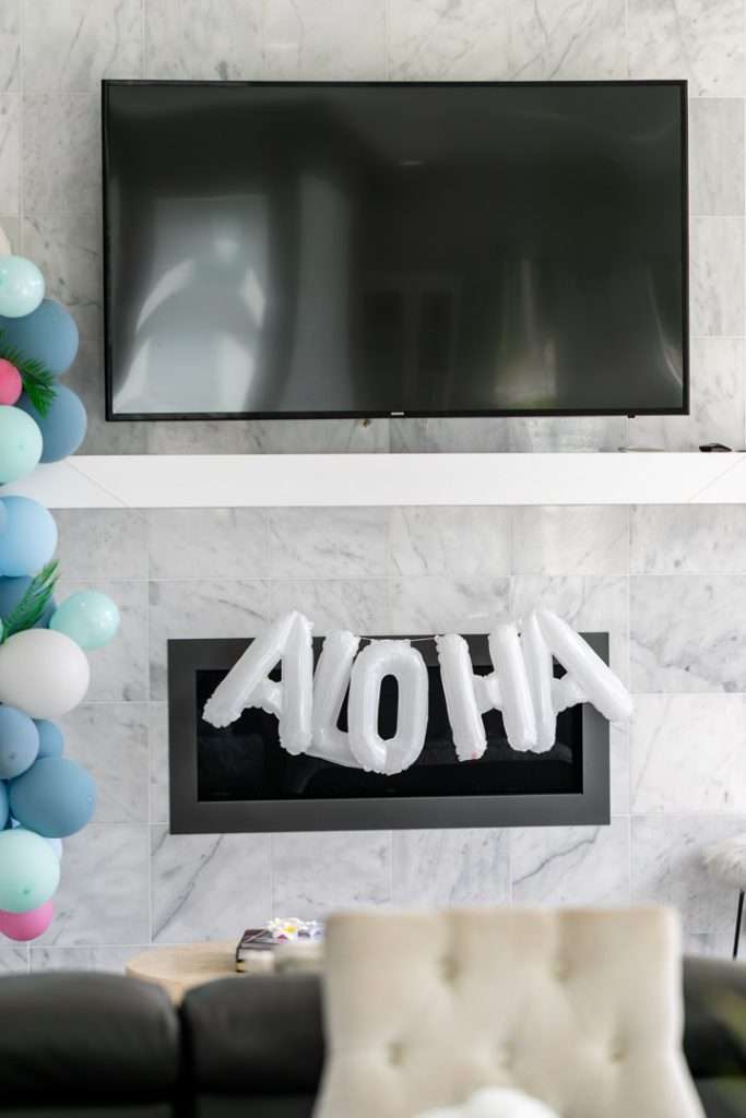 A modern tropical teen birthday party featuring a DIY dirty soda bar, colorful syrups, tropical desserts, and elevated tropical themed party decor in shades of blue and pink.
