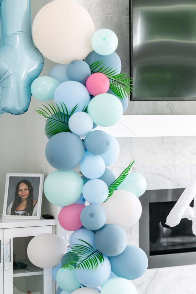 A modern tropical teen birthday party featuring a DIY dirty soda bar, colorful syrups, tropical desserts, and elevated tropical themed party decor in shades of blue and pink.