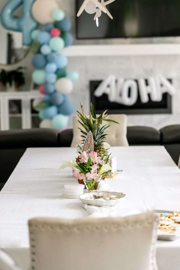 A modern tropical teen birthday party featuring a DIY dirty soda bar, colorful syrups, tropical desserts, and elevated tropical themed party decor in shades of blue and pink.