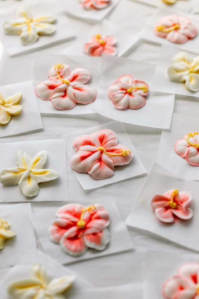 Piped hibiscus and plumeria royal icing transfers for a tropical themed teen birthday party.