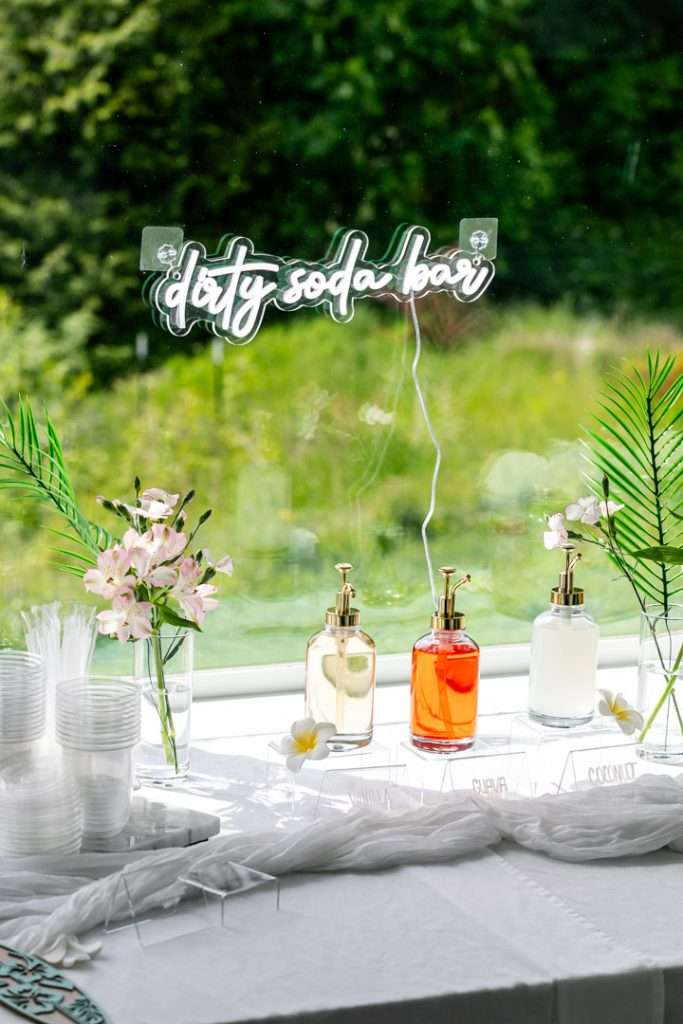 Tropical themed dirty soda bar with flavored syrups, creamer and garnishes.