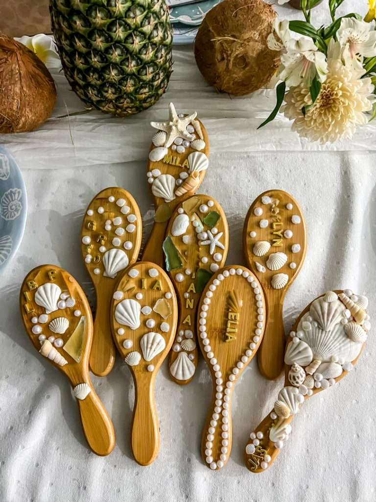 DIY hair brush decorated with seashells, pearls, and beach embellishments for creative craft and party favor.