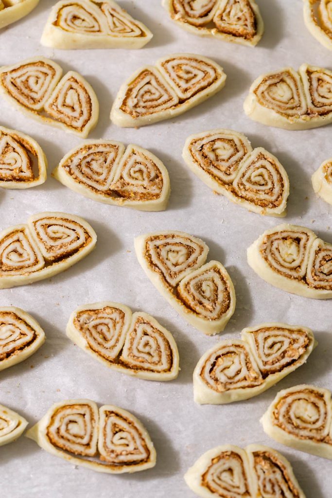 Golden apple cinnamon palmiers made with flaky puff pastry, cinnamon and apple, on a serving plate.