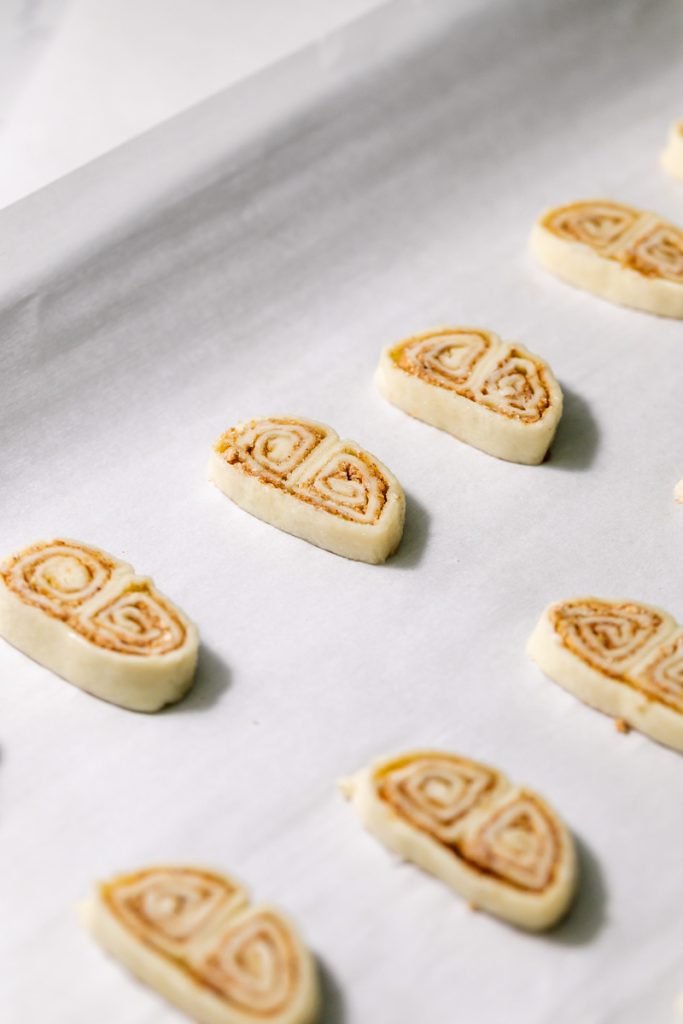 Golden apple cinnamon palmiers made with flaky puff pastry, cinnamon and apple, on a serving plate.