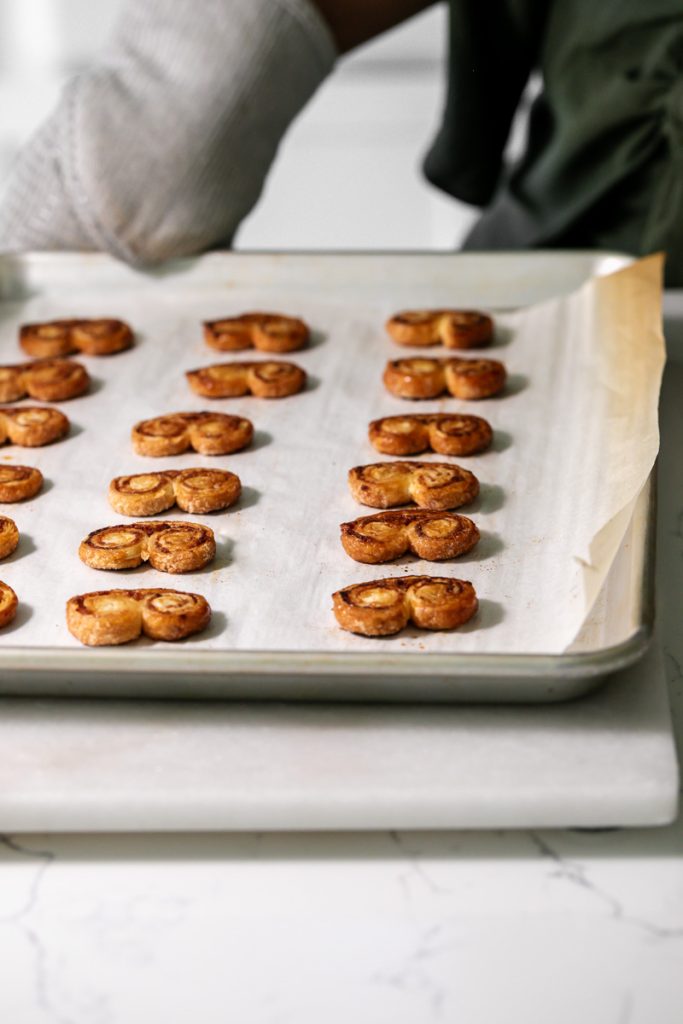 Golden apple cinnamon palmiers made with flaky puff pastry, cinnamon and apple, on a serving plate.