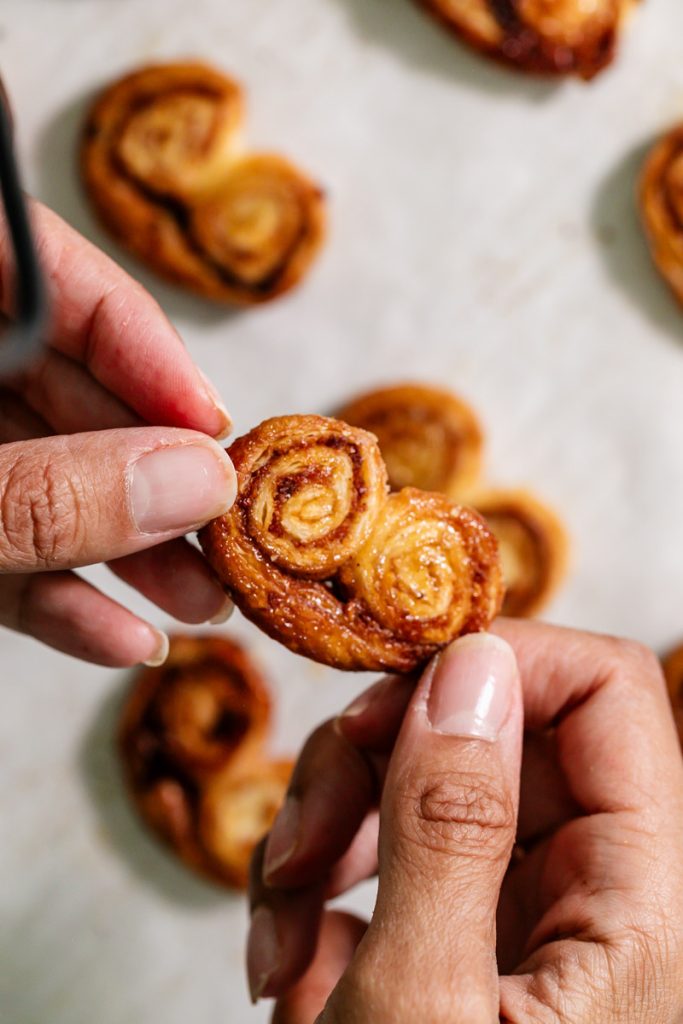 Golden apple cinnamon palmiers made with flaky puff pastry, cinnamon and apple, on a serving plate.