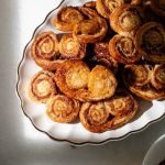 Golden apple cinnamon palmiers made with flaky puff pastry, cinnamon and apple, on a serving plate.