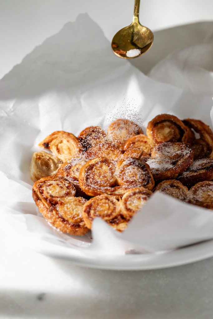Golden apple cinnamon palmiers made with flaky puff pastry, cinnamon and apple, on a serving plate.
