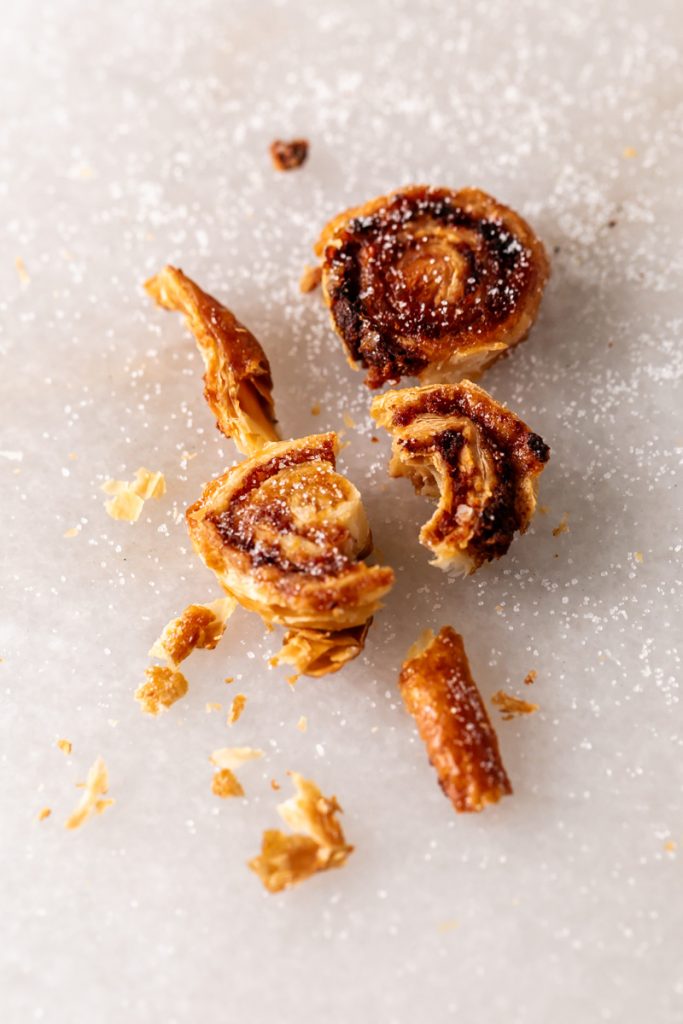 Golden apple cinnamon palmiers made with flaky puff pastry, cinnamon and apple, on a serving plate.