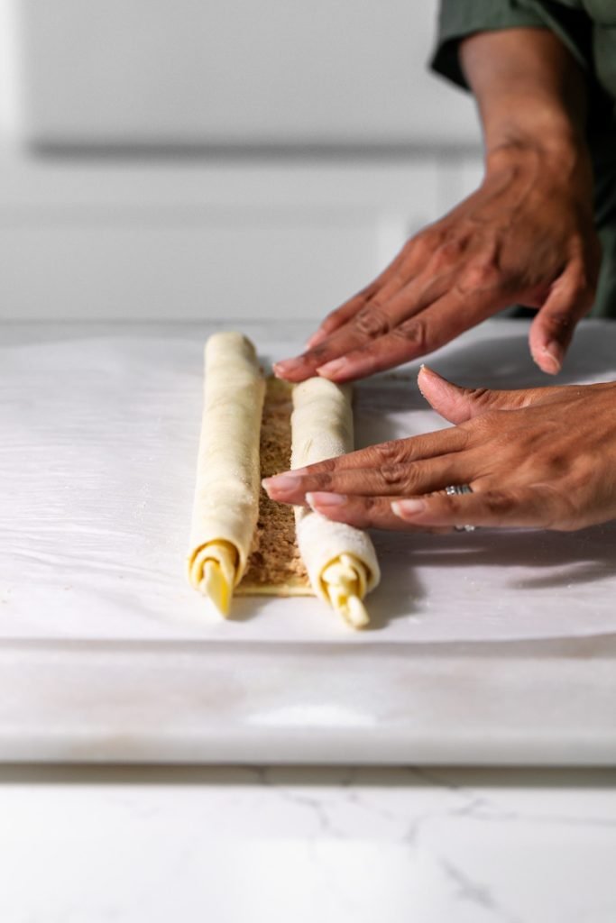 Golden apple cinnamon palmiers made with flaky puff pastry, cinnamon and apple, on a serving plate.
