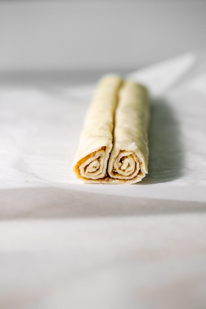 Golden apple cinnamon palmiers made with flaky puff pastry, cinnamon and apple, on a serving plate.